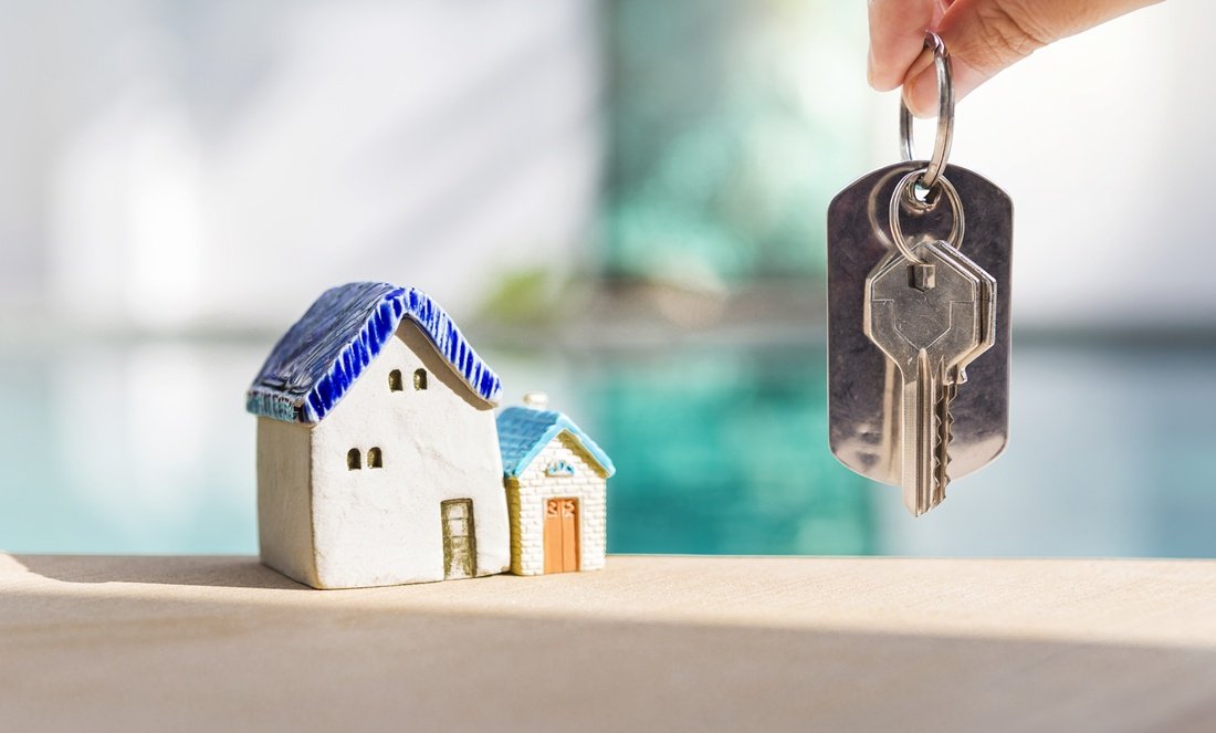 Schlüsselübergabe nach dem Immobilienkauf mit Hausmodell