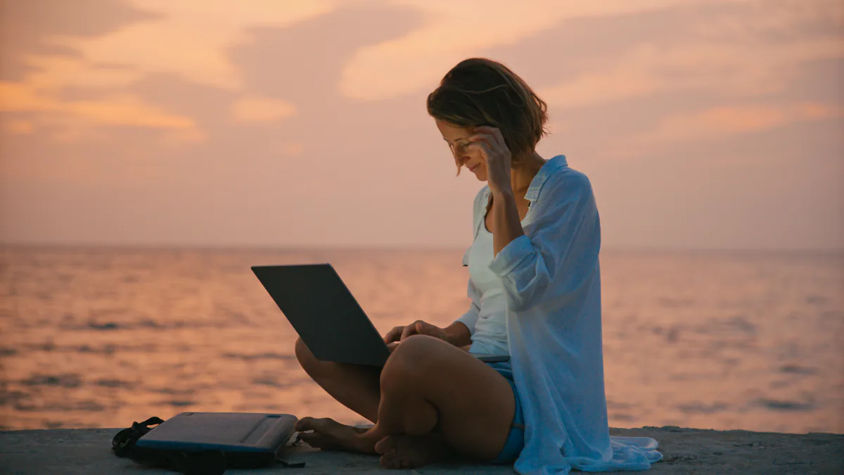 Frau arbeitet am Laptop am Meer in Istrien bei Sonnenuntergang