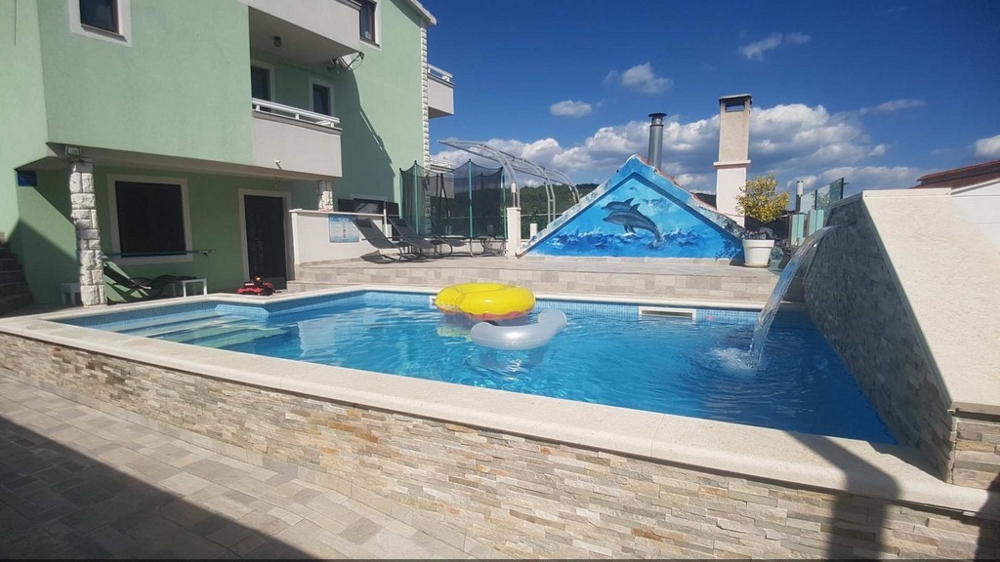 Blick von dem Liegebereich auf den Swimmingpool und die Rückseite des Hauses
