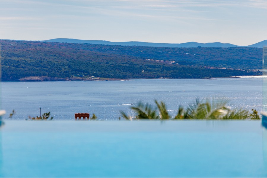 Überdachter Essbereich mit Barbecue Grill und Blick auf den Pool sowie das Meer.