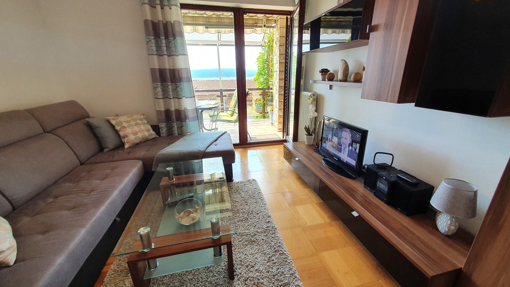 Wohnbereich mit Fernseher und Zugang zum Balkon
