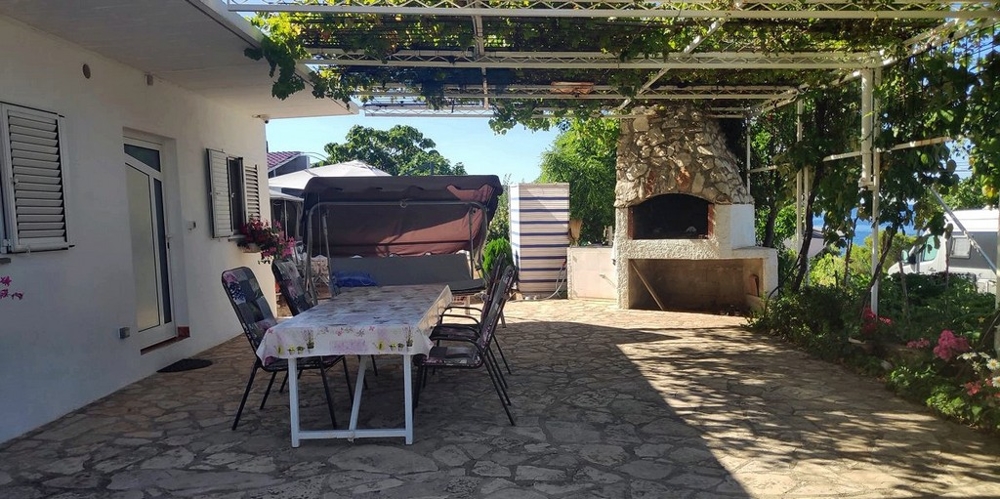 Terrasse mit überdachtem Essbereich und Barbecue Grill.