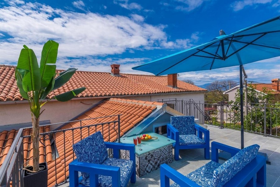Dachterrasse mit blauen Möbeln und Schirm über den Ziegeln