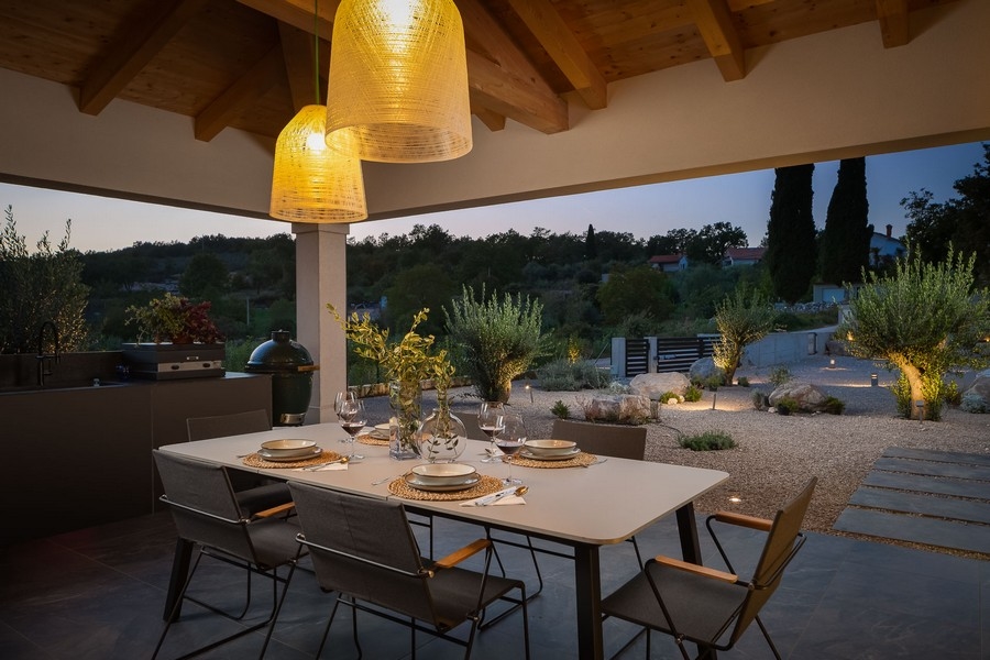 Überdachte Terrasse mit Esstisch und stimmungsvoller Beleuchtung