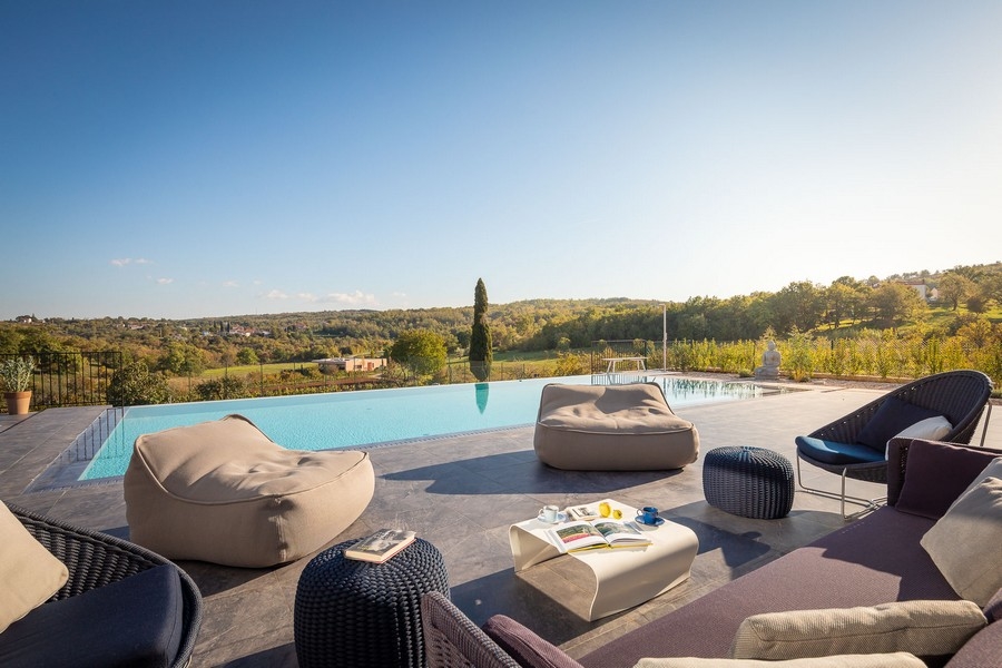 Poolterrasse mit Sonnenliegen und Blick in die Landschaft