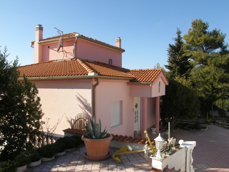 Rückseite der rosa kroatischen Villa mit Terrasse und umgeben von Bäumen