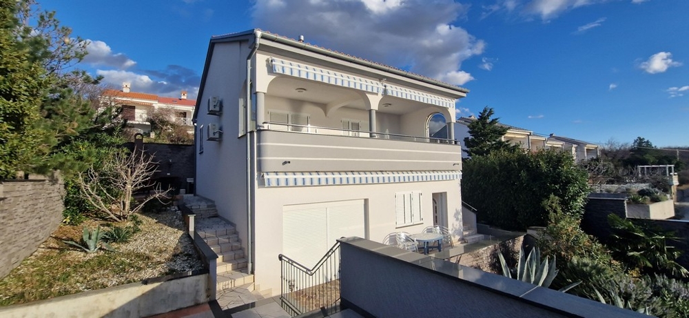 Ansicht eines weißen Hauses mit Balkon in Kroatien, zum Verkauf stehend, mit blauem Himmel im Hintergrund