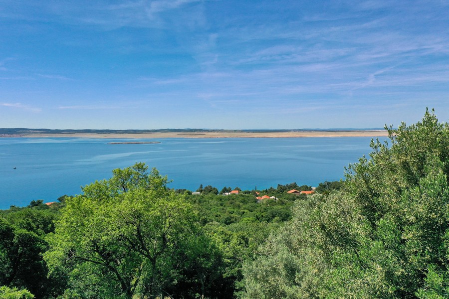 Meerblick von einem zum Verkauf stehenden Steinhaus in Kroatien, umrahmt von üppiger Vegetation und klarem Himmel.