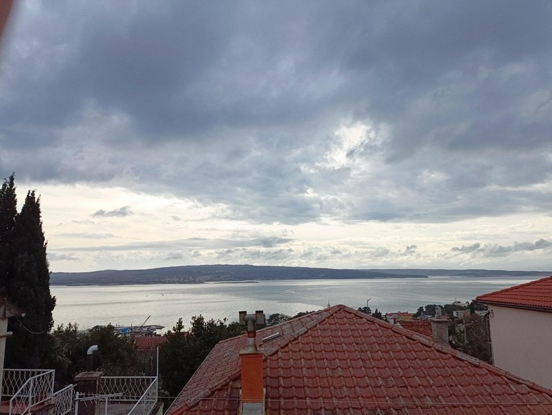 Blick auf die ruhige Adria von einer Doppelhaushälfte in Crikvenica, Kroatien, die zum Verkauf steht, mit bedecktem Himmel und hügeligem Horizont im Hintergrund