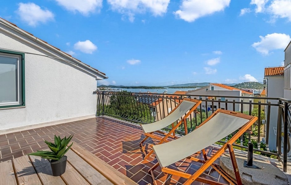 Ein Balkon mit zwei Liegestühlen und Aussicht auf die malerische Landschaft von Murter, Kroatien, Teil eines zum Verkauf stehenden Hauses.