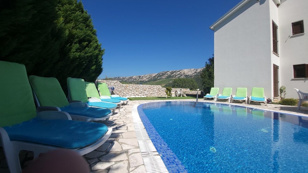 Pool mit Sonnenliegen neben dem Haus