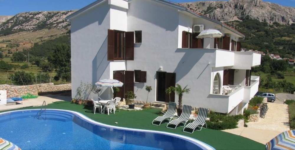 Haus mit Swimmingpool, Rasenfläche und Sonnenschirmen
