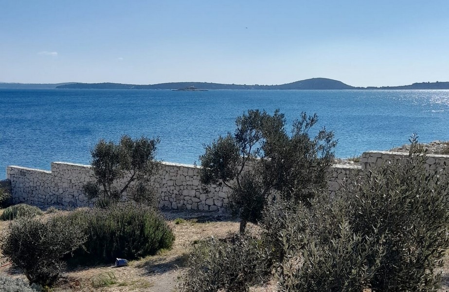 Immobilien Kroatien, Haus direkt am Meer - Panorama Scouting H3015: Blick auf das Meer von einer überdachten Terrasse mit Liegestühlen und einem Sonnenschirm.