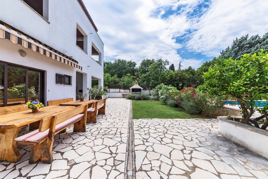 Immobilien Kroatien, Mehrfamilienhaus in Istrien mit Meerblick - Panorama Scouting H3025: Eine Terrasse mit einem langen Holztisch und Bänken, umgeben von einem gepflegten Garten