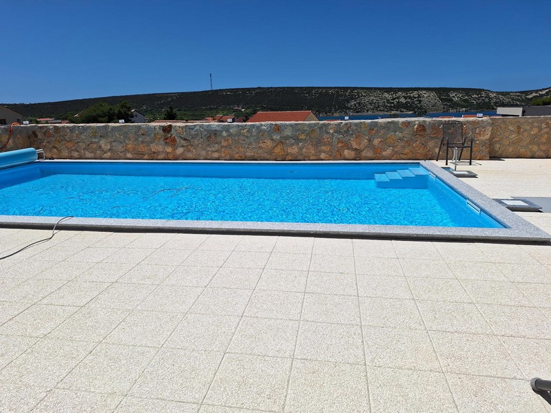 Swimmingpool und mediterrane Steinmauer auf der Sonnenterrasse.