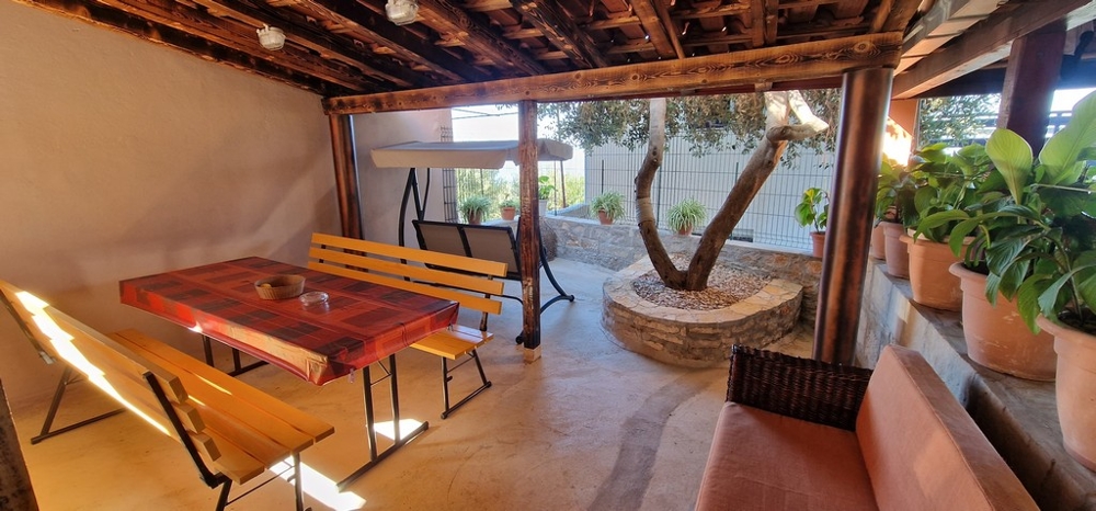 Überdachte Terrasse mit Holzbänken und Tisch