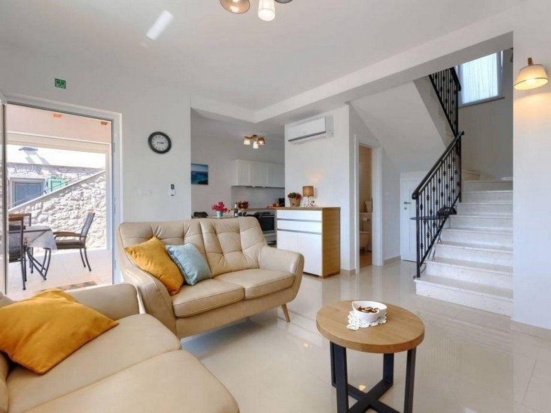 Wohnbereich mit Sofa, Treppe und Zugang zur Terrasse