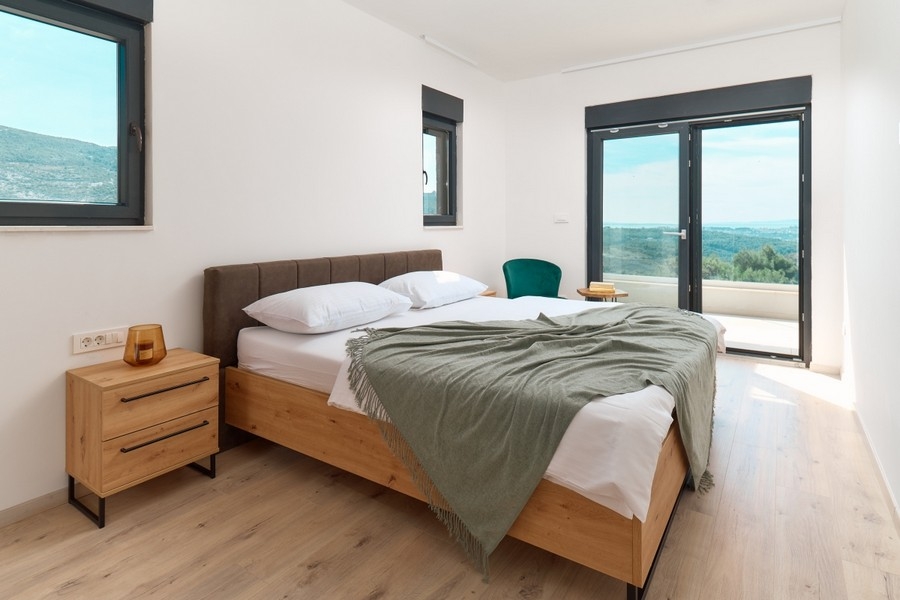 Schlafzimmer mit Doppelbett und Zugang zum Balkon mit Fernblick