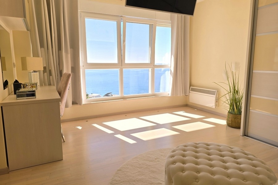 Schlafzimmer mit großem Fenster und Blick auf das Meer