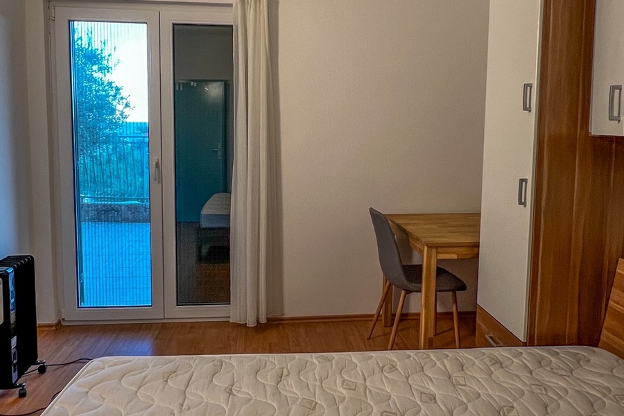 Schlafzimmer mit Balkonzugang und Schreibtisch