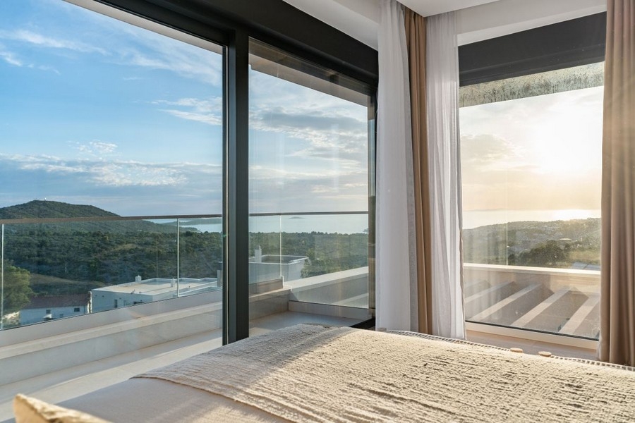 Schlafzimmer mit bodentiefen Fenstern und Panorama-Meerblick