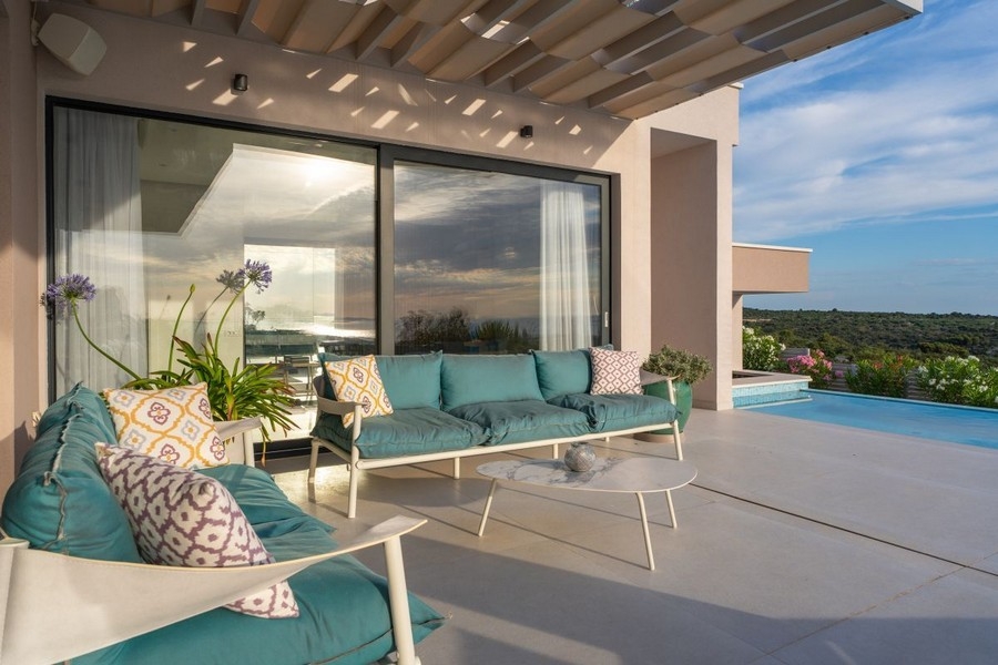 Überdachte Terrasse mit Lounge und Blick auf Pool und Meer