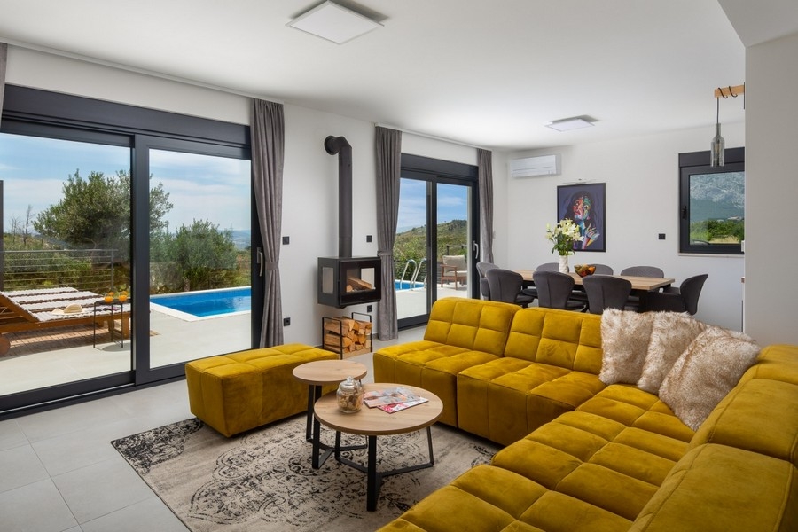 Wohnbereich mit Sofa, Kamin und Zugang zur Poolterrasse