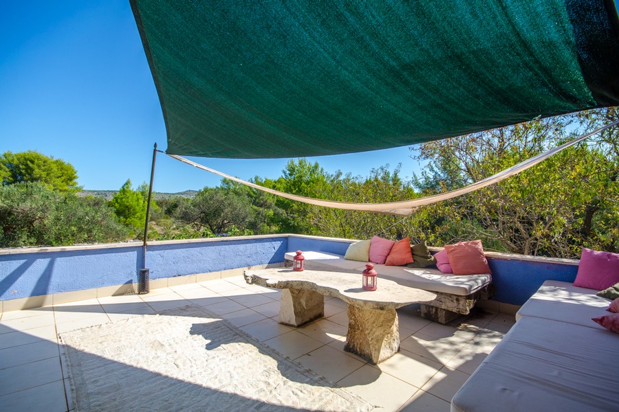 Überdachte Lounge-Terrasse mit Sitzbereich und mediterraner Umgebung