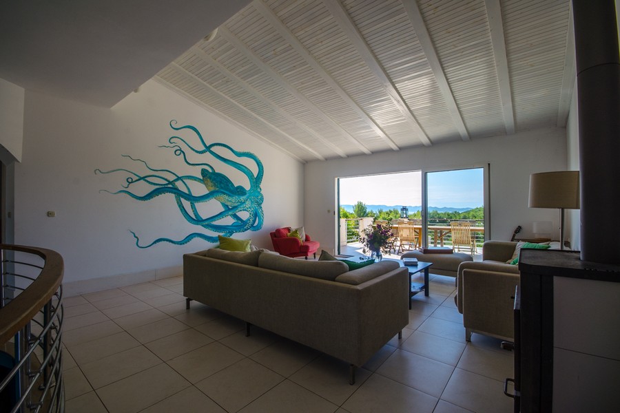 Wohnbereich mit Sofa, Kaminofen und Zugang zur Terrasse