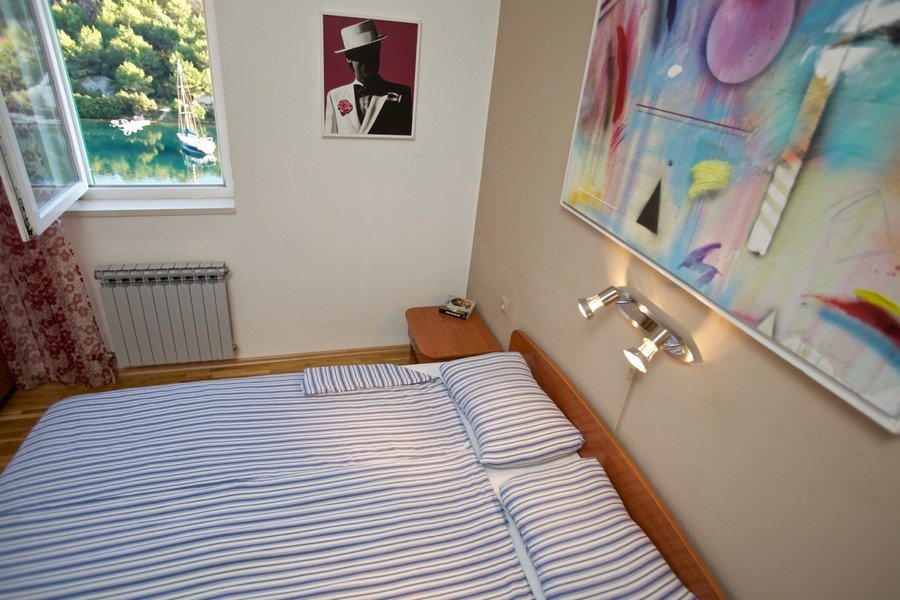 Schlafzimmer mit Fensterblick auf Bucht und Segelboot