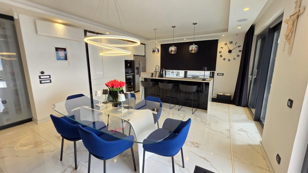 Essbereich mit Glastisch und moderner Küche