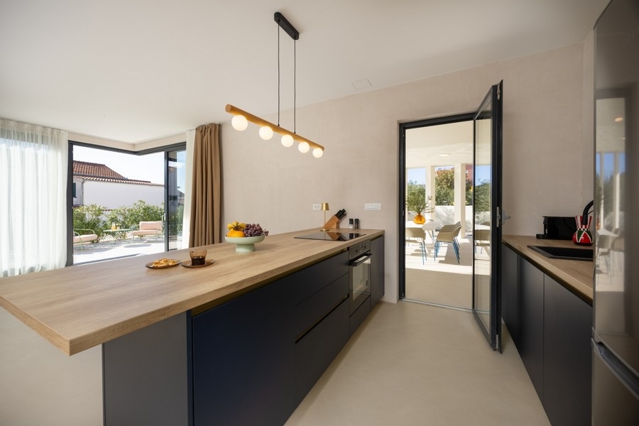 Moderne Küche mit Kochinsel und Zugang zur Terrasse