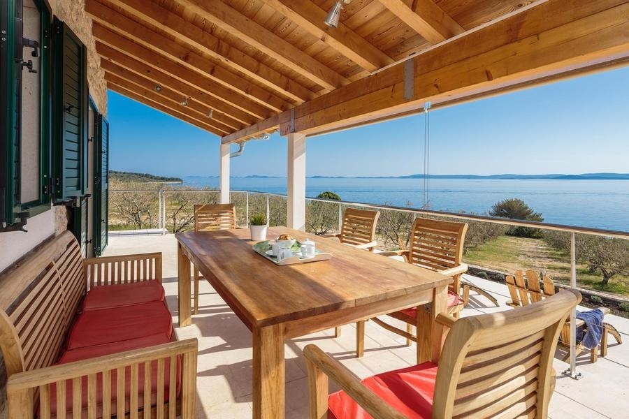 Überdachte Terrasse mit Tisch und Meerblick