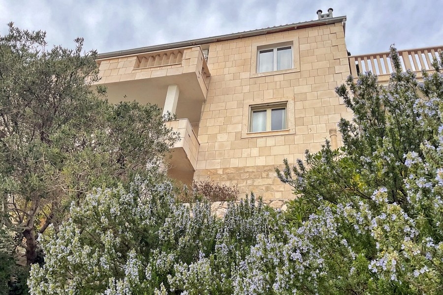 Hausfassade aus Naturstein mit Balkon und Garten