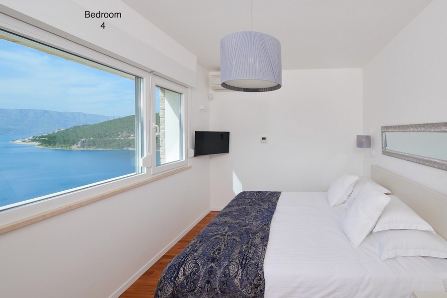 Schlafzimmer mit Panoramafenster und Blick auf Meer und Insel