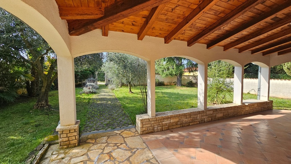 Überdachte Terrasse mit Sitzgruppe und Gartenblick