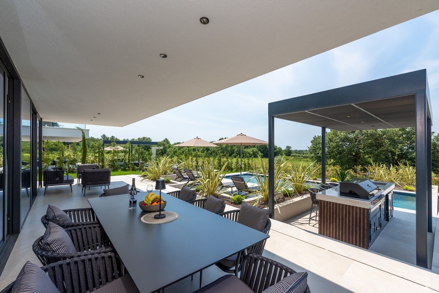 Überdachte Terrasse mit Essbereich und Außenküche am Pool