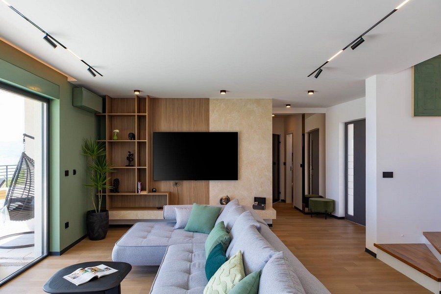 Offener Wohnbereich mit TV Wand und Design Treppe
