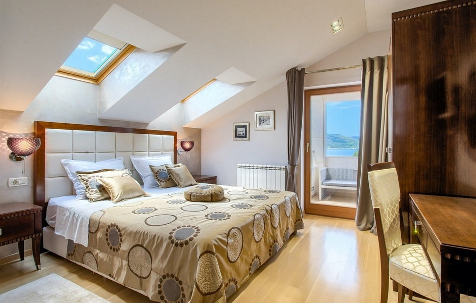Schlafzimmer mit Dachschrägen und Zugang zum Balkon mit Meerblick