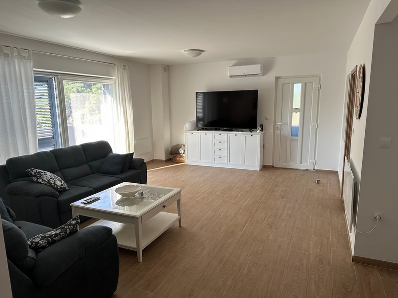 Wohnzimmer mit Sofa, TV und Zugang zum Balkon in moderner Ausstattung