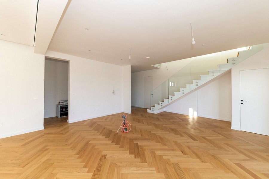 Heller Wohnraum mit Parkettboden und moderner Treppe aus Glas