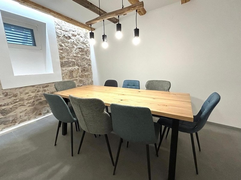 Überdachter Essbereich im Innenraum mit Holzbalken und Beleuchtung