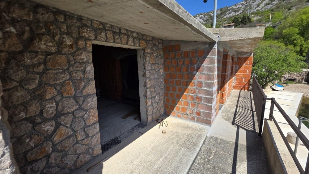 Außenbereich mit Natursteinmauer und überdachter Terrasse
