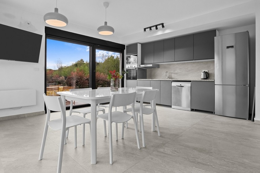 Moderner Wohn- und Essbereich mit offener Küche und Zugang zur Terrasse