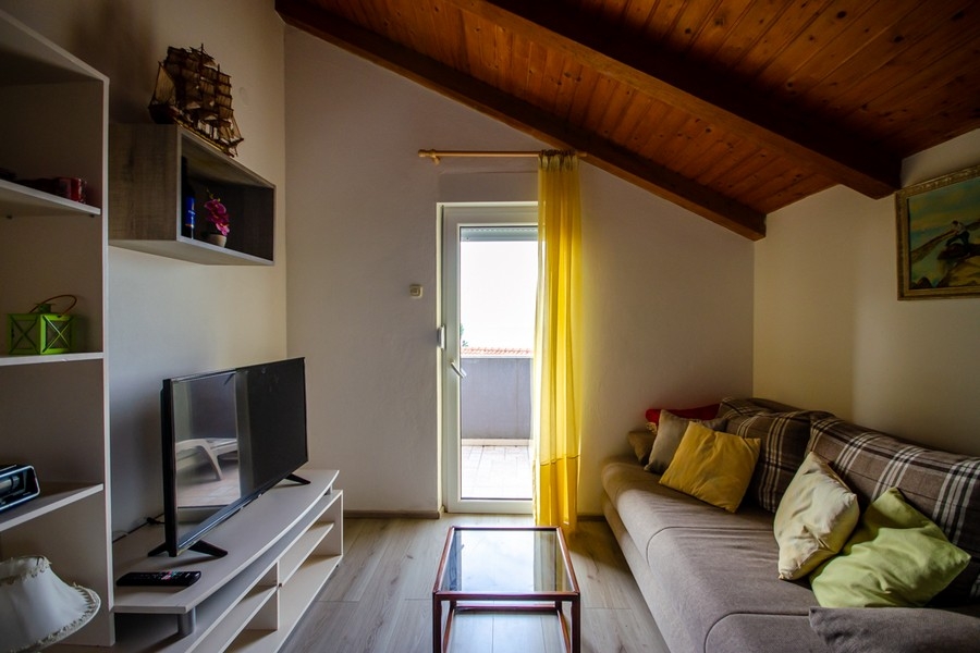 Wohnraum im Dachgeschoss mit Sofa und Zugang zum Balkon