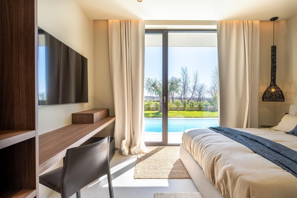 Schlafzimmer mit direktem Blick in den Garten und Pool