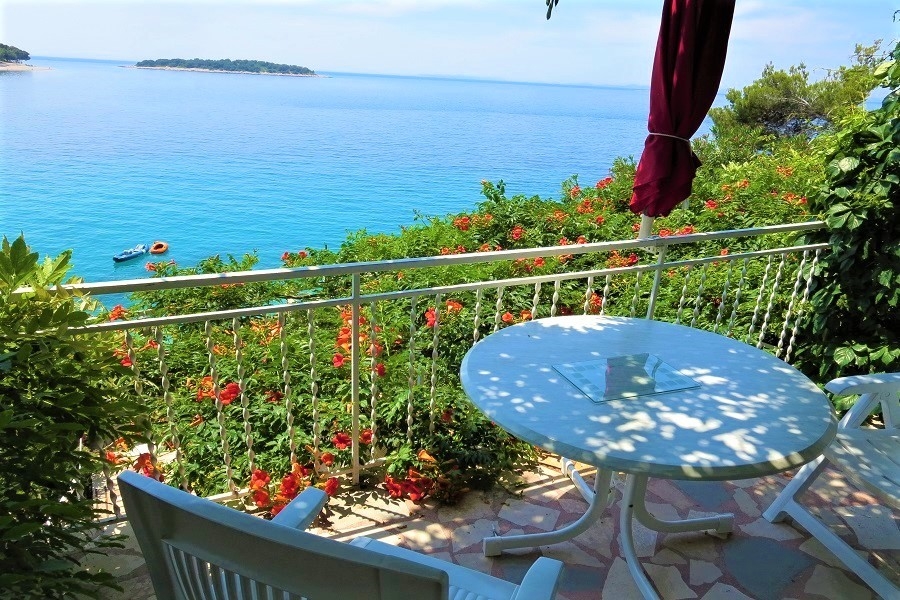 Terrasse mit Meerblick und Sitzgruppe unter Sonnenschirm