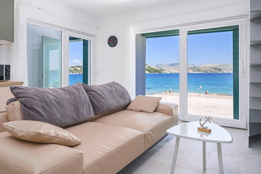 Wohnzimmer mit Sofa und direktem Blick auf das Meer