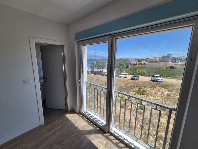 Schlafzimmer mit großflächigen Fenstern und Zugang zu einem Balkon mit Meerblick.