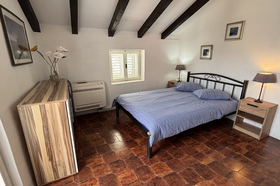 Helles Schlafzimmer mit sichtbaren Holzbalken im dalmatinischen Steinhaus